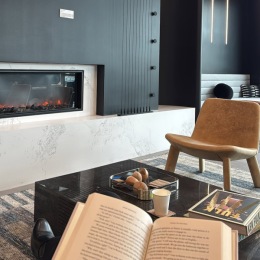 As the winter season approaches, we welcome you to enjoy our cozy amenity spaces such as our lobby and our clubroom with comfy seating and warm firewalls. Nothing like reading a good book with coffee by the fireplace! ☕️?? a person reading a book in a community lounge with a fireplace