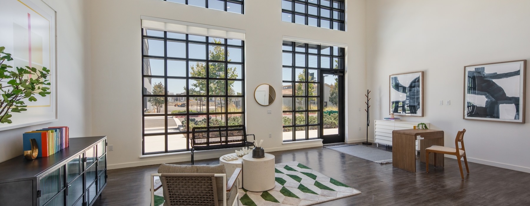 a room with large windows, chairs and a desk with a chair