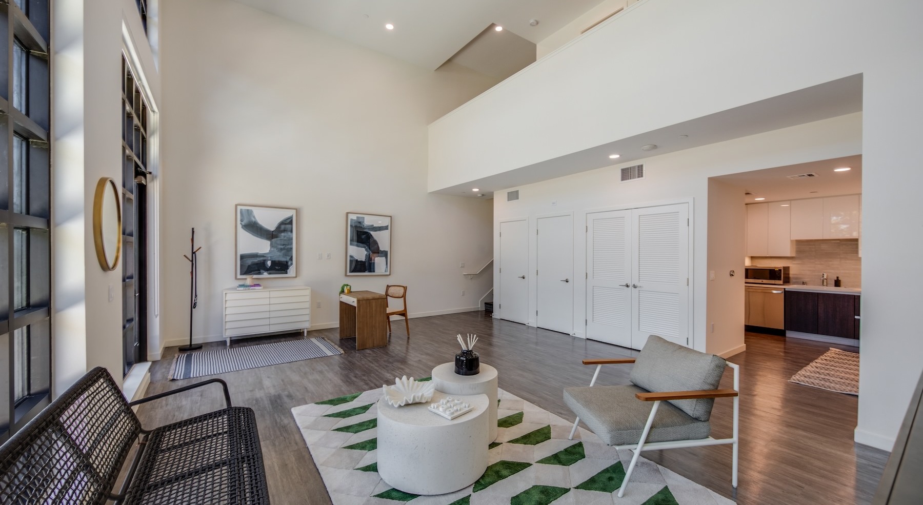 a room with large windows, chairs and a desk with a chair