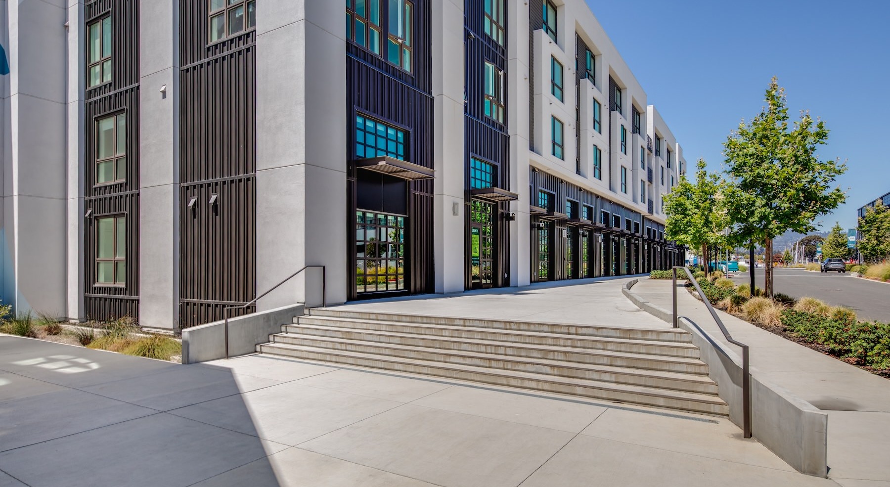exterior of a building with a sidewalk and trees next to a street
