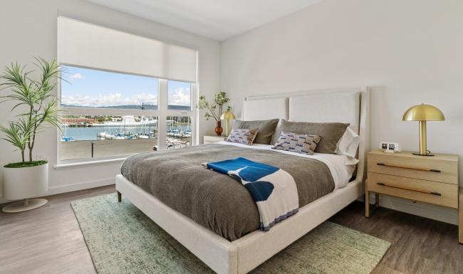Bedroom options to fit every lifestyle Bedroom with large window with view of the waterfront at Launch Alameda apartments for rent.